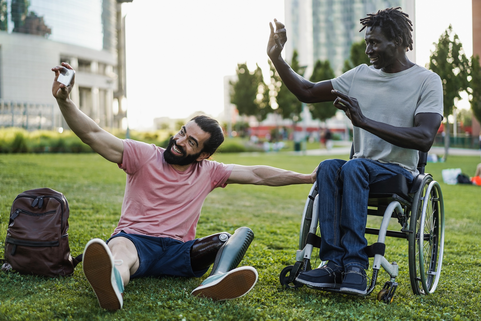 Multiracial friends with disability having fun doing video call at park city