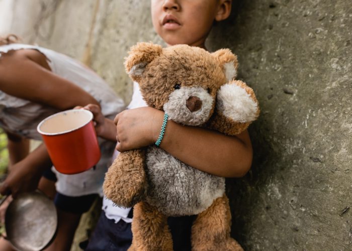 Cropped view of homeless african american children with dirty teddy bear begging alms in slum