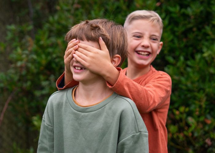 Two happy children playing hide and seek in green park, guessing game